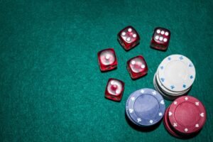 Dados rojos y fichas de casino apiladas sobre un tapete verde